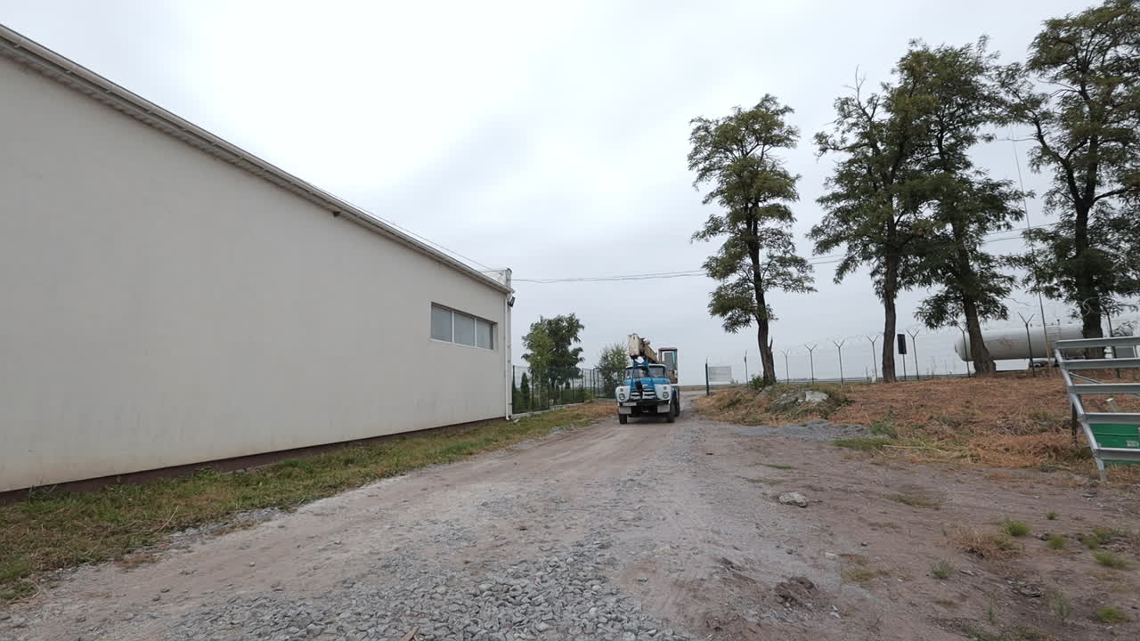 Truck with Crane on a Dirt Road near a Building