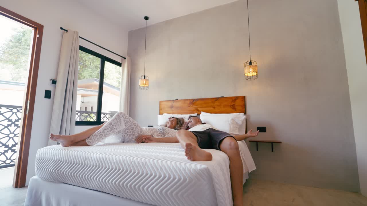 Happy Couple Jumping and Relaxing on a Bed in a Modern Bedroom