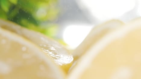 seguimiento a lo largo de limones medio cortados con partículas de agua cayendo en cámara lenta, enfoque en rack