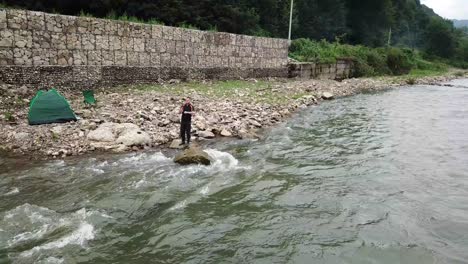a male fisherman catches fish on a stormy mountain river spinning predatory fish a male fisherman catches fish on a stormy mountain river spinning predatory fish aerial view