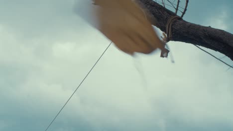 torn old damp fabric canvas from tent tied on branch blowing in wind refugee camp