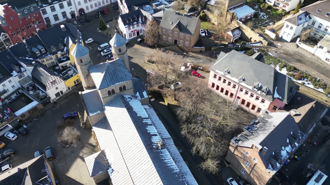 Dynamic orbiting drone shot around the medieval church tower and marketplace.