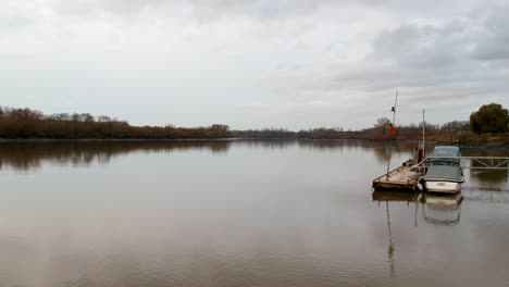 Schwenken-Sie-An-Einem-Bewölkten-Tag-über-Ein-Flussdock-Mit-Kleinen-Booten-Und-Angelruten