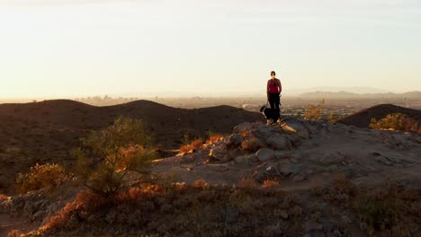 Luftumlaufbahn-Um-Eine-Frau-Mit-Ihrem-Hundefreund,-Die-Den-Sonnenuntergang-In-Arizona-Genießt