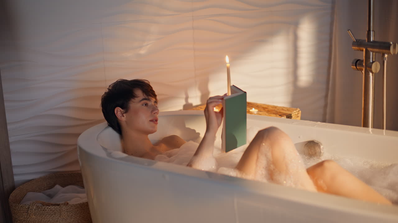 Chilling lady read novel enjoying spa procedures bath. Calm woman lying bathroom