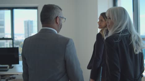 female manager leading business partners into meeting room