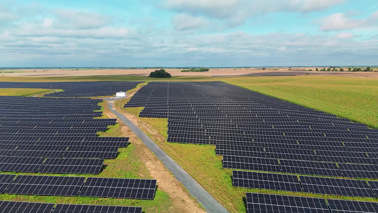 Fotovoltaisk solcellepark og adgangsvej i landligt landskab.