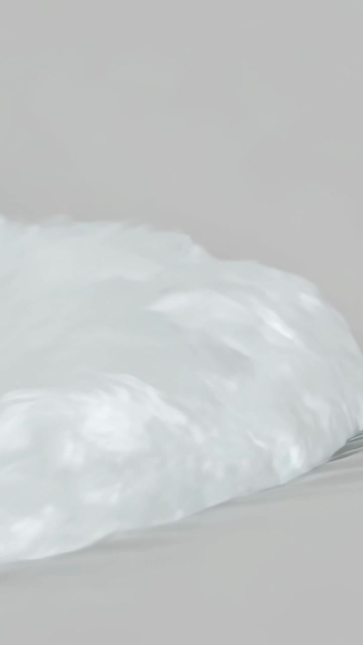 Video verticale: Telecamera che si sposta più a destra, mostrando una texture a cumulo bianco su un letto di tessuto, parete grigia.