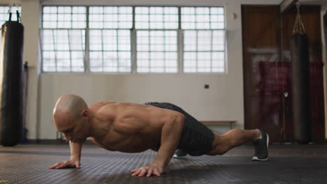 hombre calvo caucásico musculoso sin camisa haciendo ejercicios, haciendo flexiones