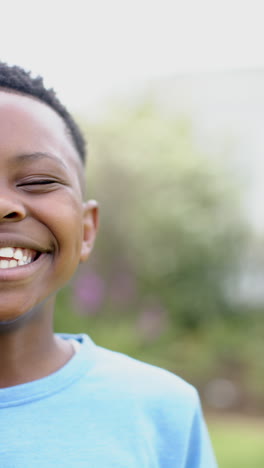 vertical video: african american boy wearing blue shirt, smiling wide outdoors