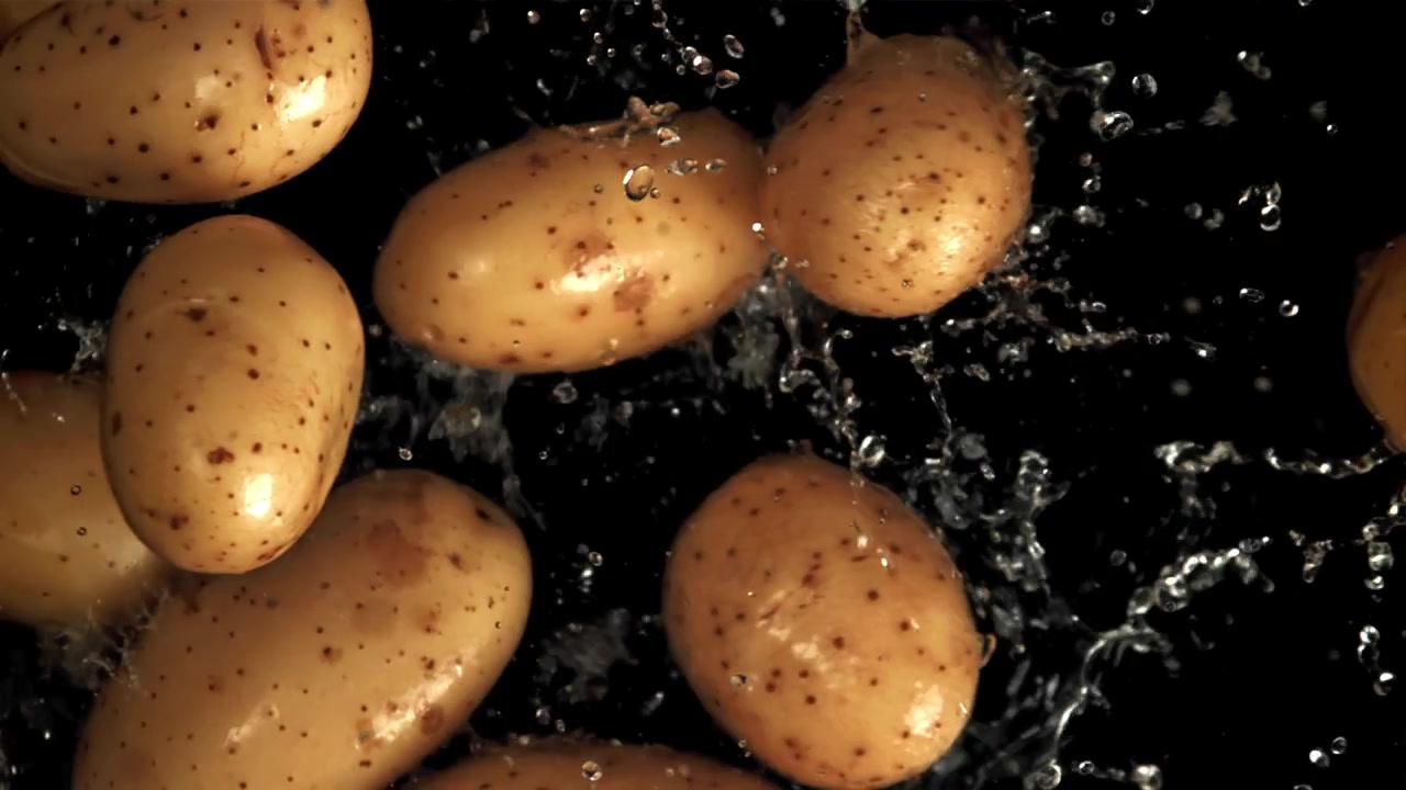 Patate fresche che cadono e creano schizzi d'acqua su sfondo nero