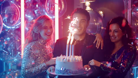 hombre y mujer lindos sosteniendo pastel en una fiesta. amigos felices soplando velas en el club