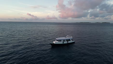 drone close up boat in the indian ocean at sunset for divers exploring the maldives coral reef