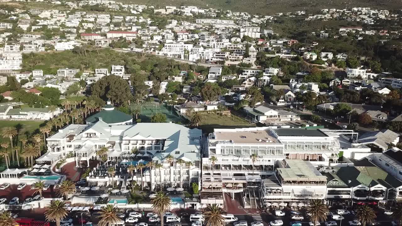 flying backwards tilting up from the hotels at the beach over the city camps bay to the 12 apostles mountains
