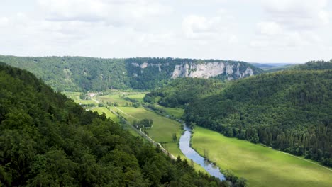 aerial view of idyllic valley next to green forest in hilly landscape