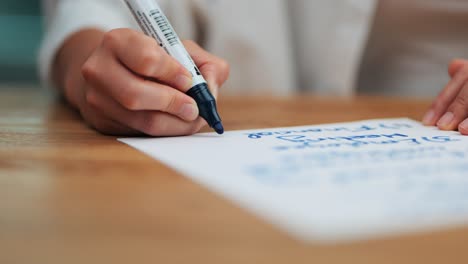 tormenta de ideas de negocios: primer plano de la mano de la mujer escribiendo con marcador azul en papel en una mesa de madera