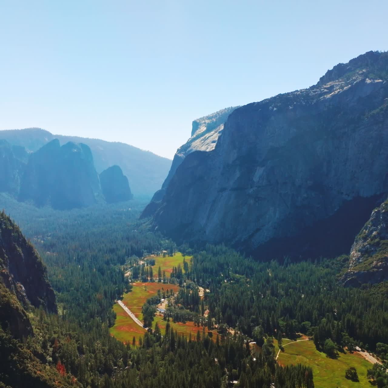 Pine tree woods growing on the mountains and valley. Sunlit panorama of amazing rocks at Yosemite National Park, California, USA. Aerial view