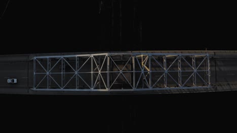 straight down aerial view of a parker truss bridge over a river with vehicular traffic