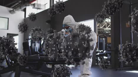 multiple covid-19 cells floating over group of health workers cleaning the gym using disinfectant