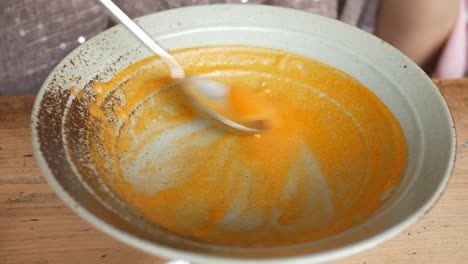 stirring a bowl of yellow vegetables soup