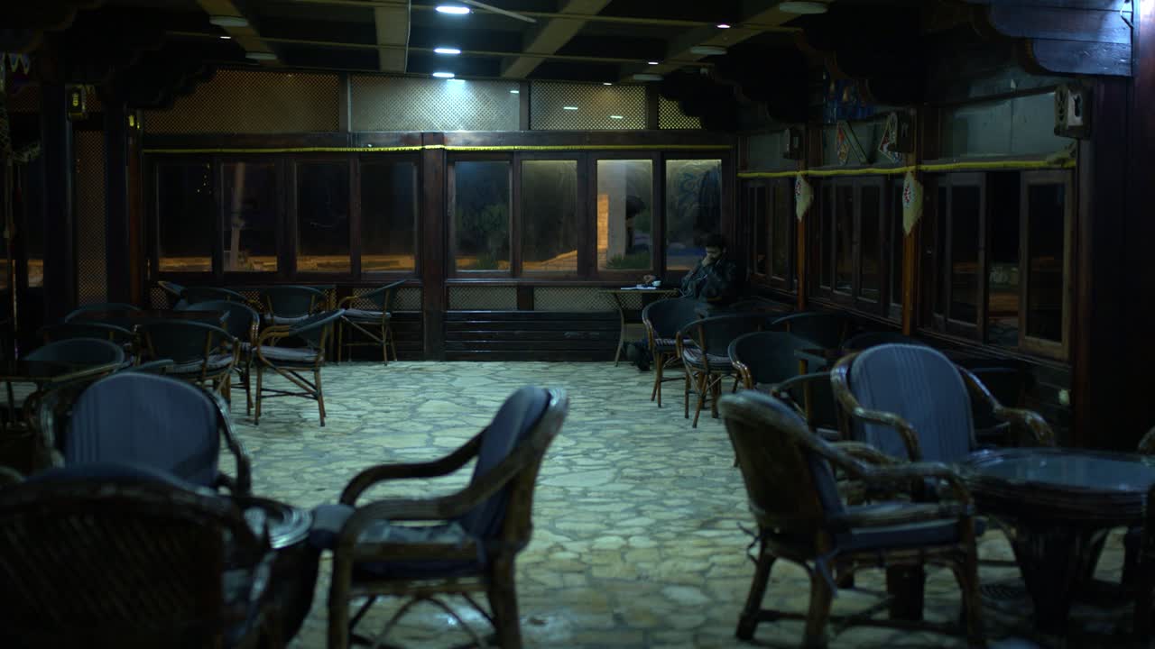 한 남자가 카페의 모 ⁇ 이에 앉아 있고 조명이 꺼져 있습니다.