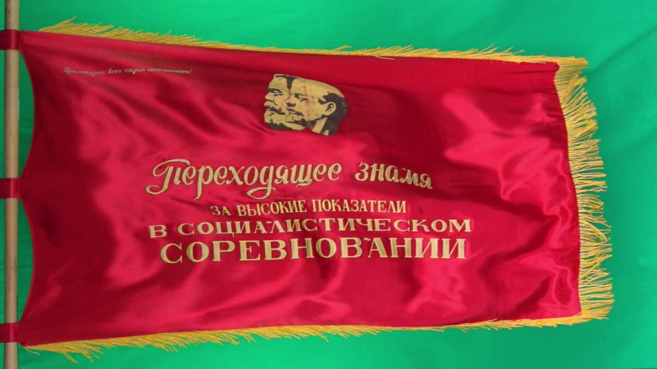 una bandera de desfile soviética que representa a marx y lenin vuela en cámara lenta contra un fondo de pantalla verde
