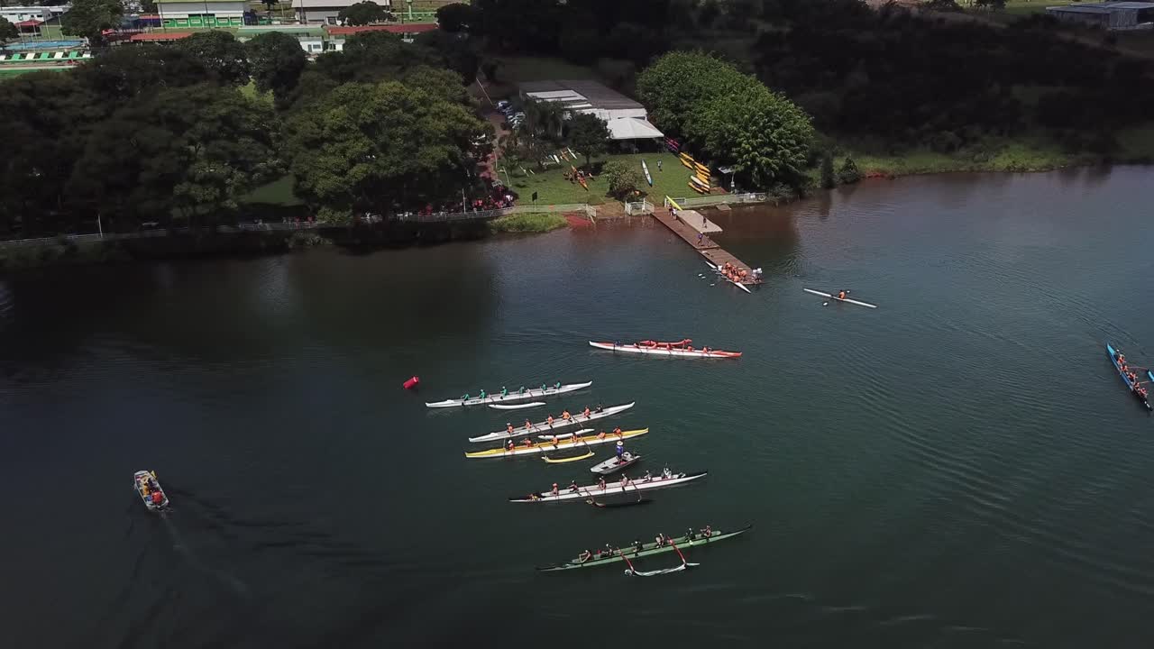 vista aérea descendente hacia un colorido grupo de atletas largos botes de remos en el agua del lago