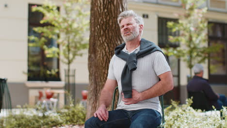 mature man feeling sudden strong abdominal stomach ache gastritis problem poisoning diarrhea outdoor