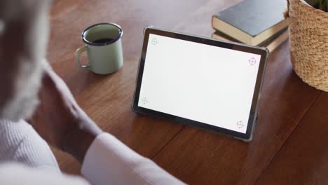 Senior-african-american-man-sitting-at-table-and-using-tablet-with-copy-space,-slow-motion