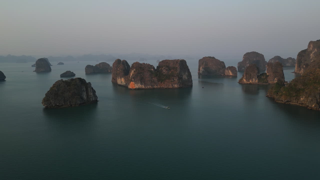 Aerial 4K drone footage over Ha Long Bay, Vietnam, showing tourist boats navigating among limestone karsts and emerald waters