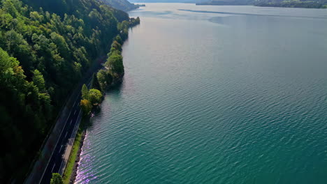 Cinematic-view-of-coastal-road-with-driving-car-near-lake-Attersee,-aerial-view