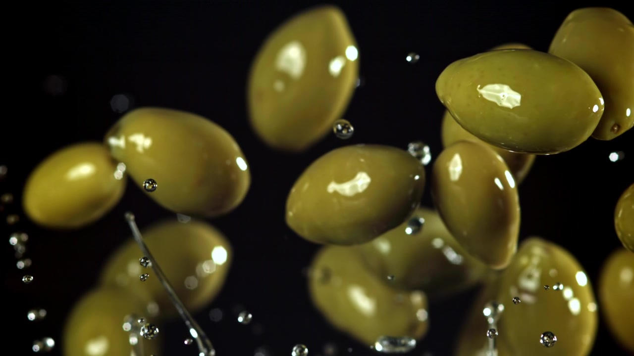 Olive verdi fresche e goccioline d'acqua che cadono al rallentatore