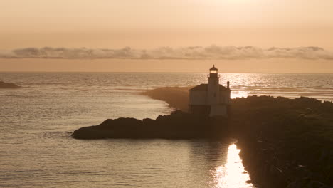 silhouette of coquille river lighthouse in bandon, oregon, usa. drone pull-back shot at sunset.
