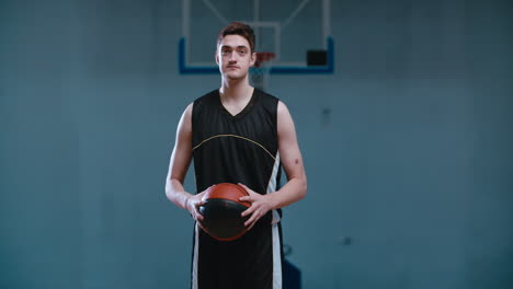 retrato de media longitud de un jugador de baloncesto caucásico posando con una pelota en el interior. 4k uhd