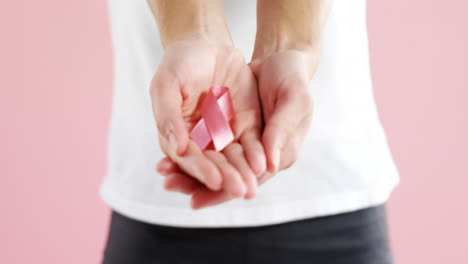 Mid-section-of-woman-holding-breast-cancer-awareness-ribbon