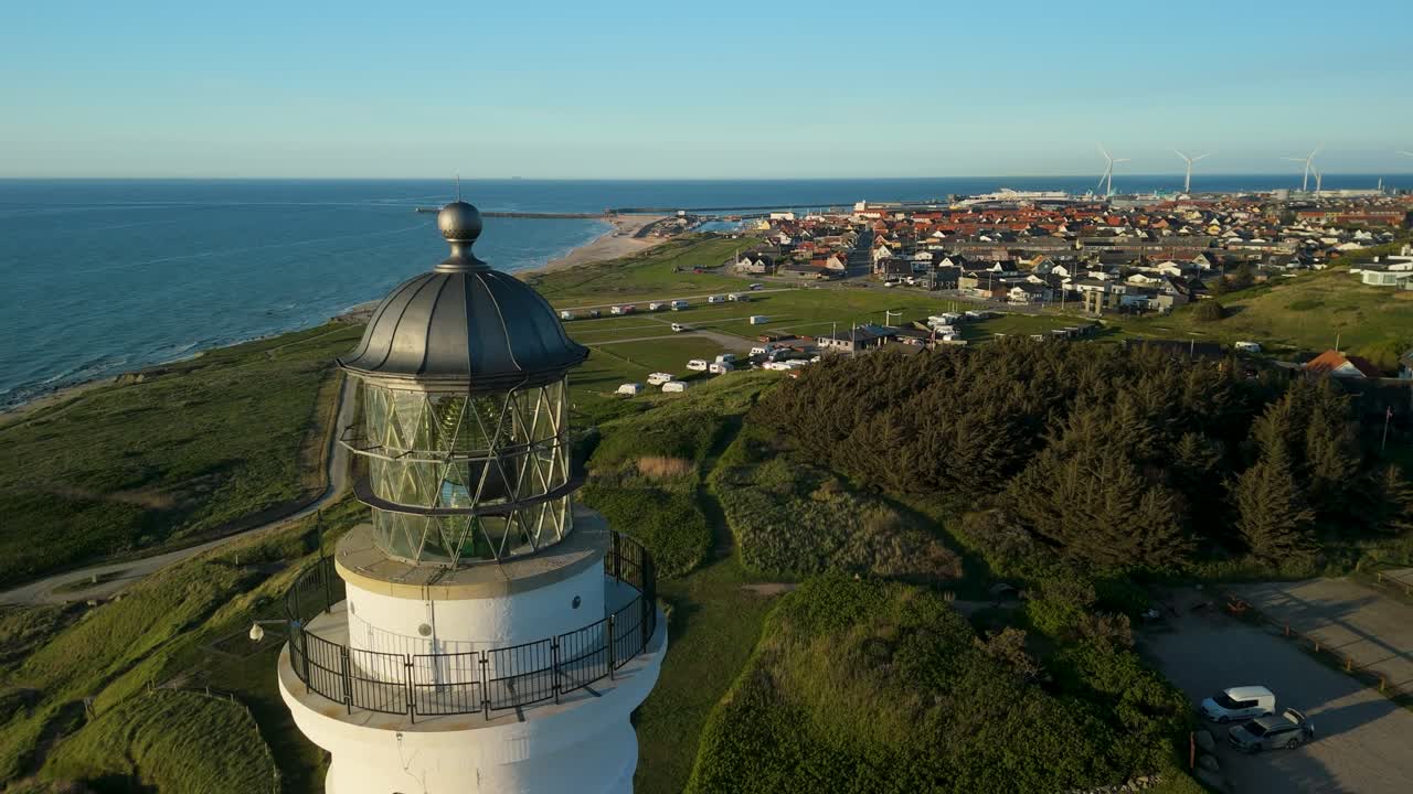 Orbit af det historiske, hvide Hirtshals Fyr, der viser de barske kystklitter og Vesterhavet ved solnedgang i Nordjylland
