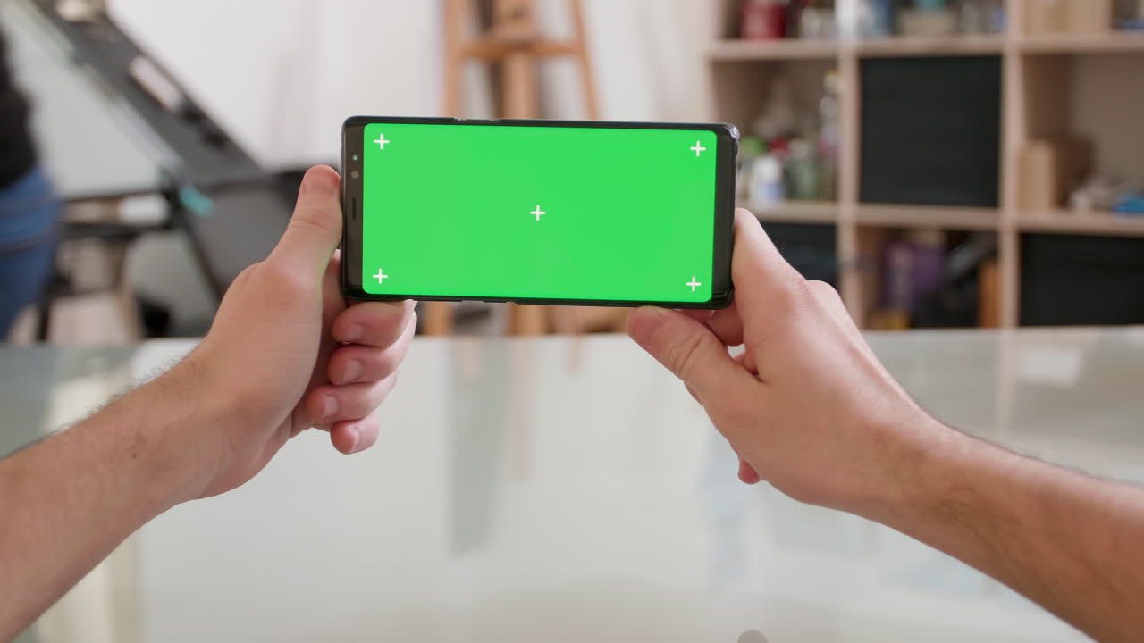 Smartphone with green screen held by hands