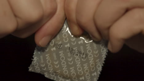 manos luchando para abrir el paquete de condones