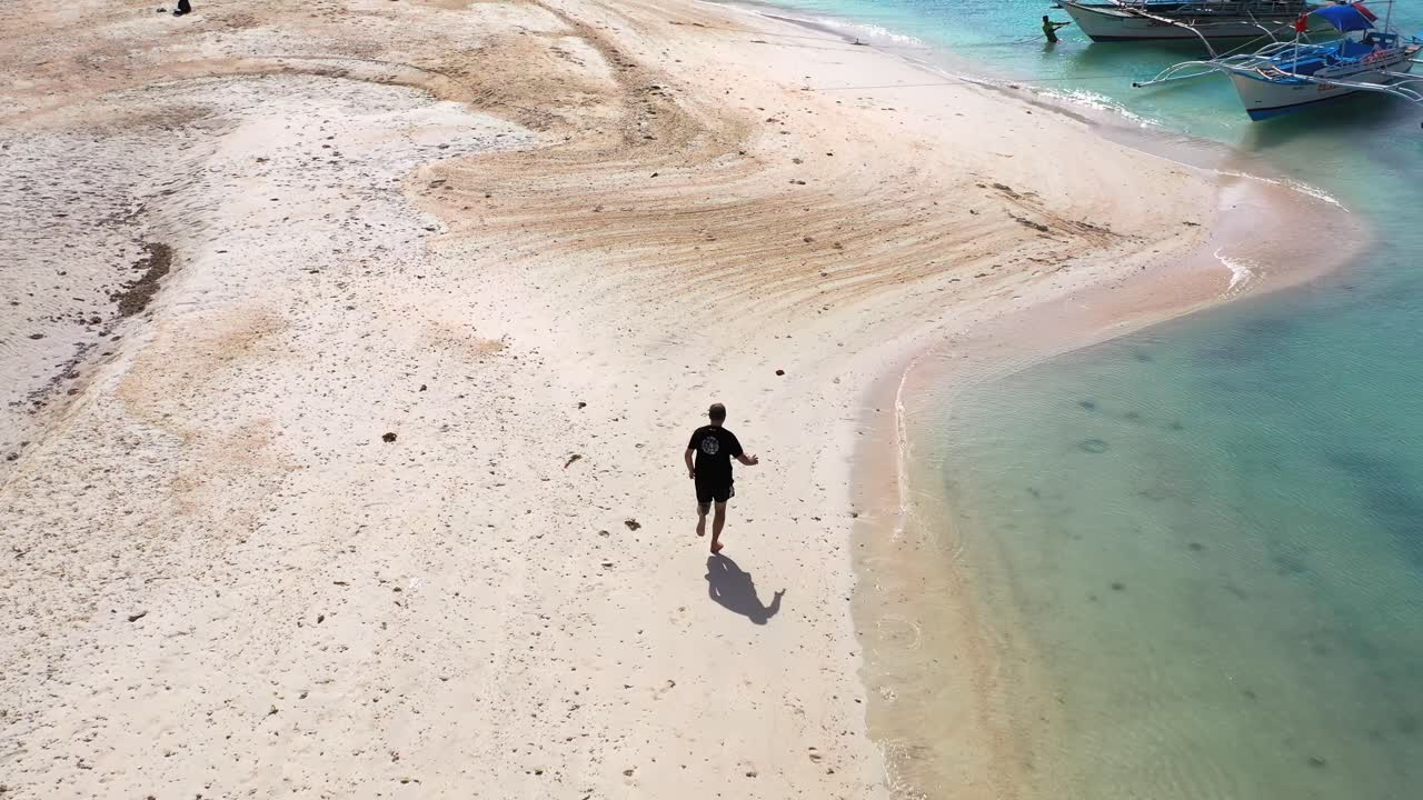 Arial view of man jog on beach sand by the sea, bangka boats, Boracay