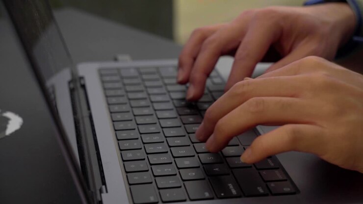 Detailaufnahme von Händen, die in Zeitlupe (60 fps) auf einem Laptop tippen