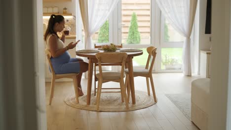 a pregnant woman enjoying her daily routine at home, relaxing in the living room and eating in the kitchen. the scene highlights comfort, maternity, and moments of self-care in a cozy setting