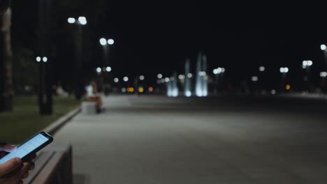 man using smartphone at night in a park