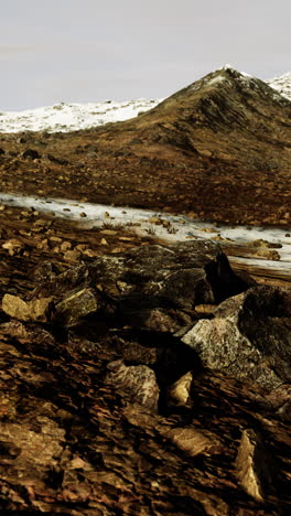 a snowy mountain landscape with rocks in the foreground