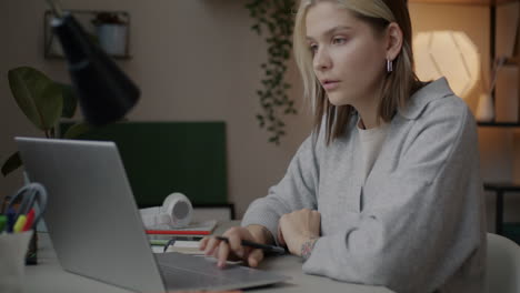 una mujer joven estudiando en una computadora portátil.
