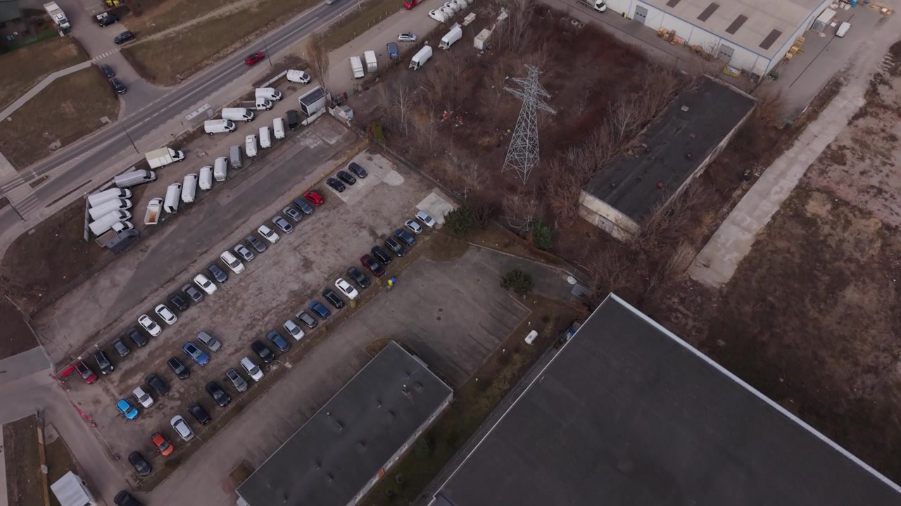 Aerial Delivery Fleet Yard In Warszawa Showing Lined Vans, Parking Bays And Staging Area Dispatch Coordinator Arranges Routes And Inspects Readiness In Neutral Winter Light