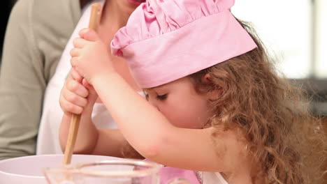 una niña preparando masa con su madre.
