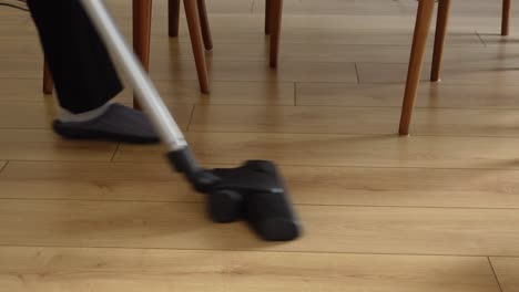 a woman in slippers vacuuming the floor