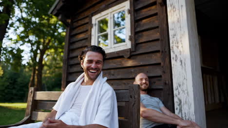 two men laughing and relaxing outdoors by a rustic cabin