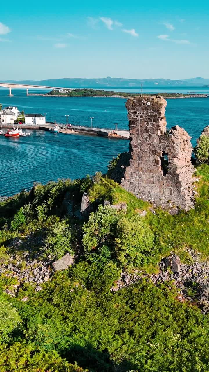 Panoramica aerea di rovine e di un villaggio costiero in Scozia.