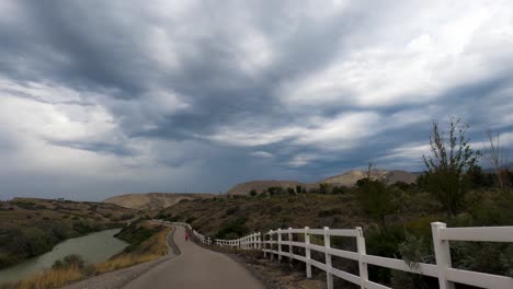 riding a bicycle along a nature trail by a river on an overcast day - first person view